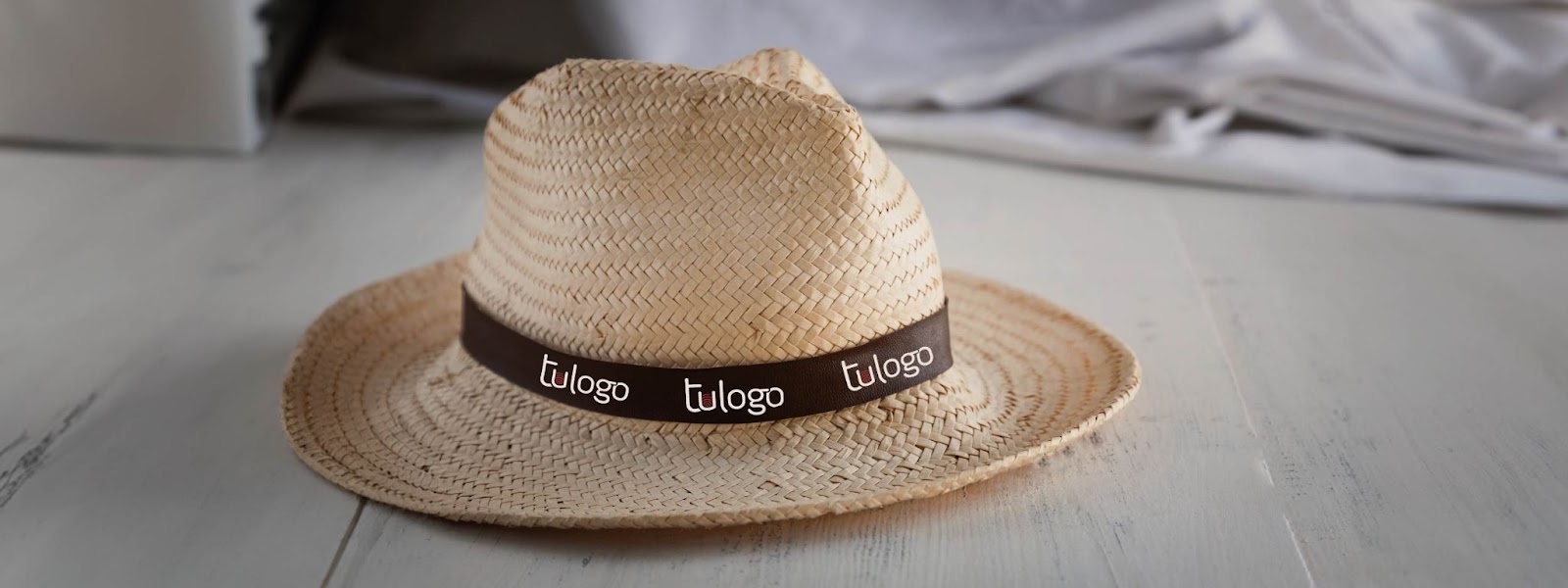 Sombrero de paja con una cinta alrededor con la frase "tu logo"