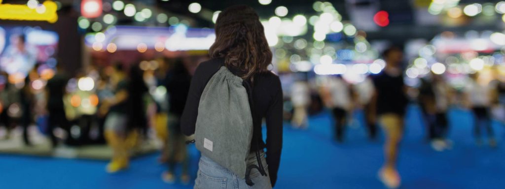 Mujer recorriendo los stands de una feria con una bolsa de cuerdas