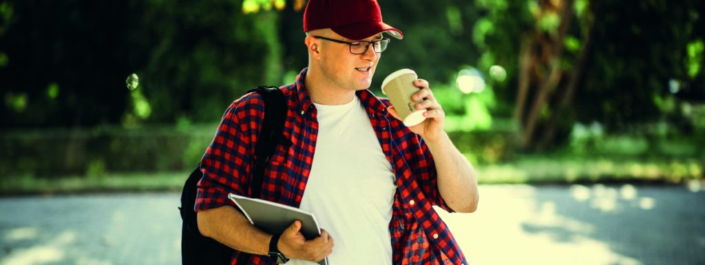 joven caminando con un vaso de café para estudiar