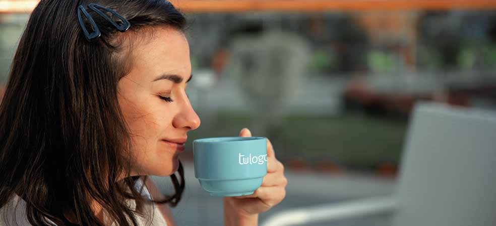 mujer disfrutando del aroma de un café en una taza personalizada