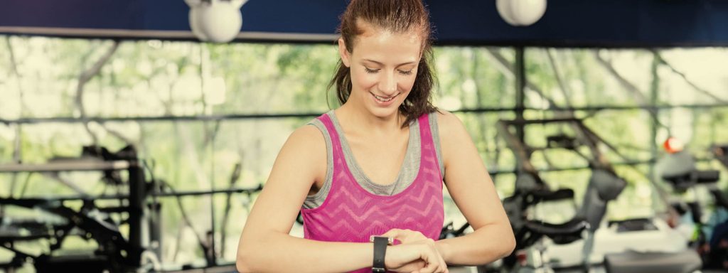 chica joven mirando su smartwatch en el gimnasio