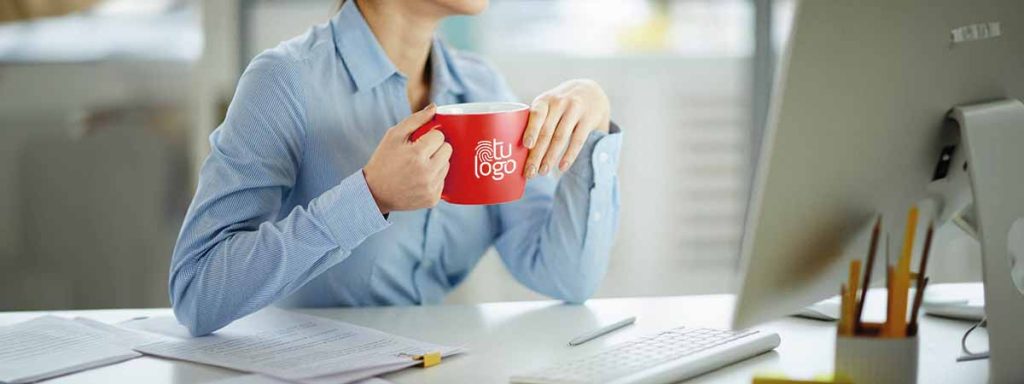 mujer tomando una taza de café mientras trabaja en su portátil