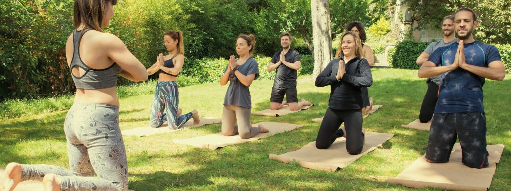 personas practicando yoga al aire libre en colchonetas