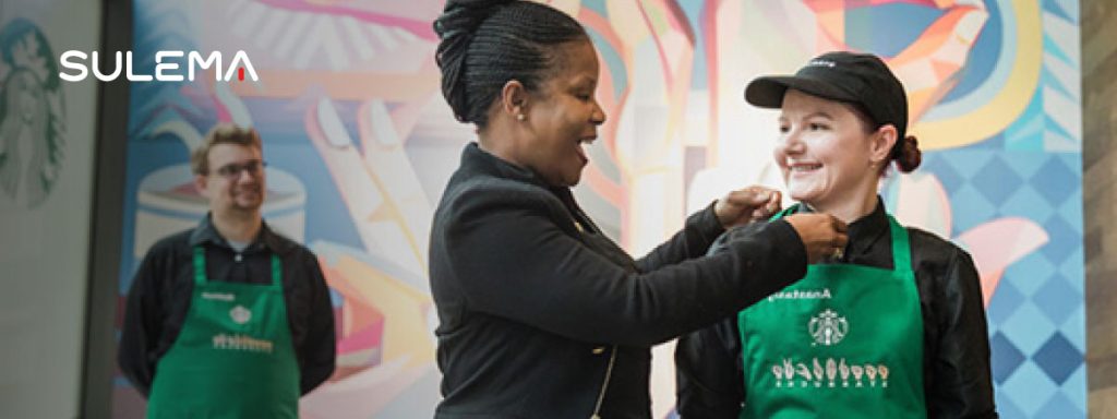 Mujer otorgando un reconocimiento a una joven barista de Starbucks.