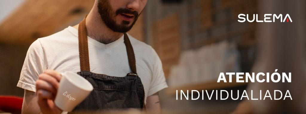 Texto: "Atención individualizada", se ve a un barista con delantal y una taza personalizada que dice "tu logo"