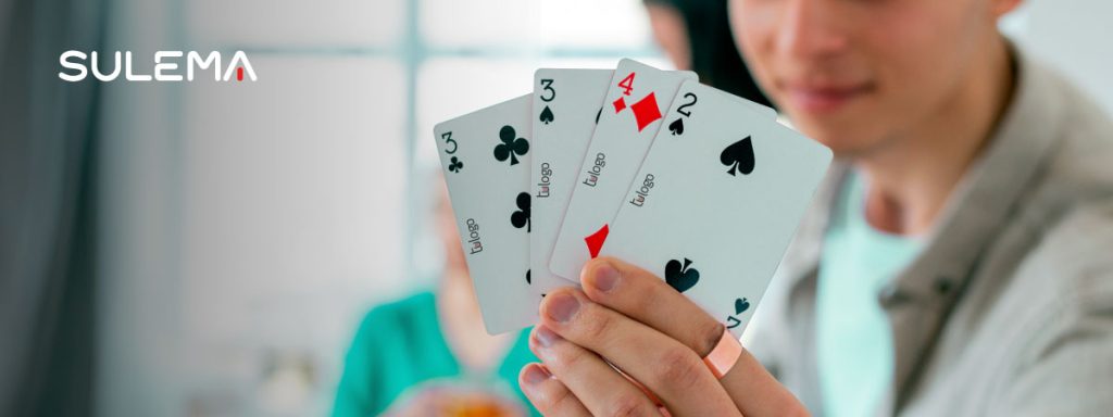 joven mostrando su mazo de cartas de póker personalizadas con tu logo