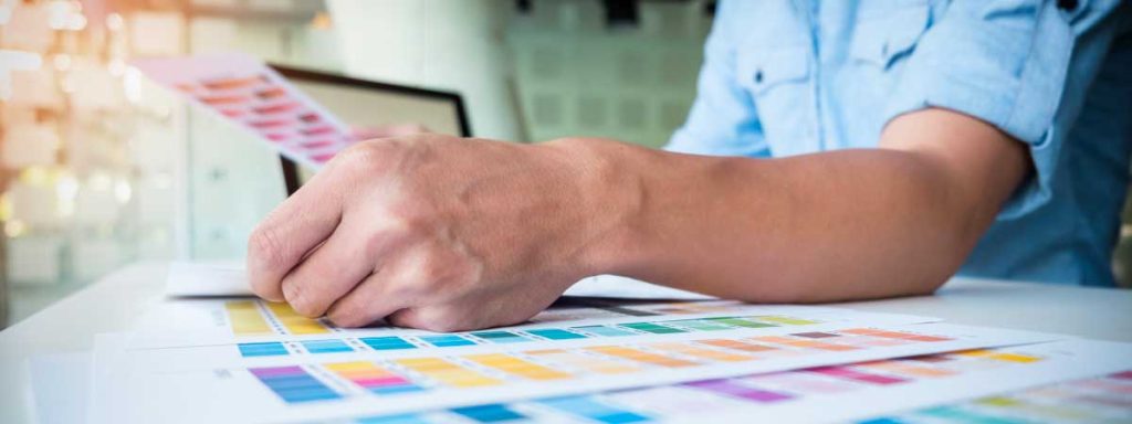 La importancia de seleccionar los tonos de color deseados Hombre seleccionando fichas de colores Pantone