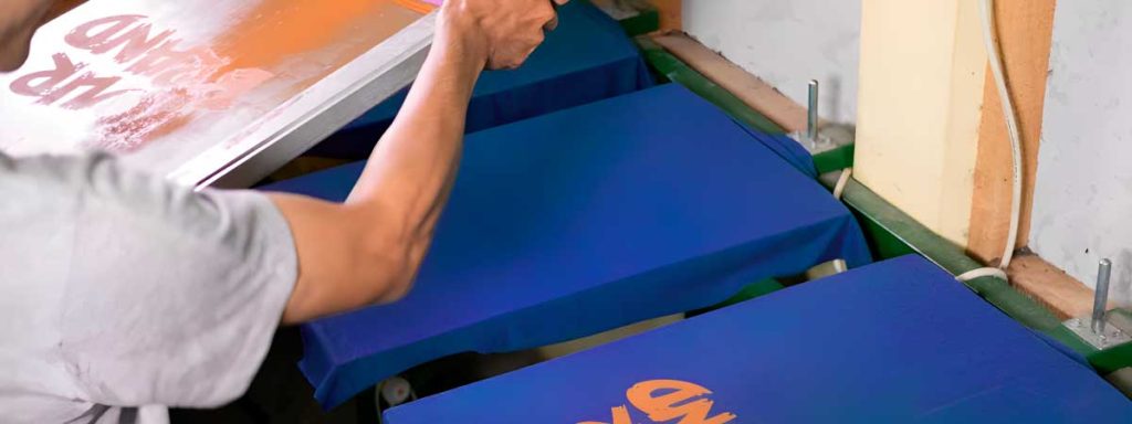 Hombre personalizando camisetas con serigrafía