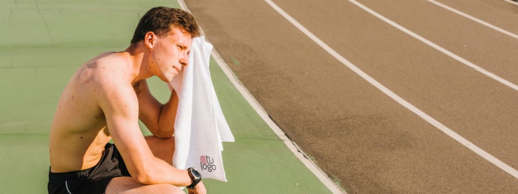 Hombre secándose con toalla deportiva luego de un entrenamiento de atletismo